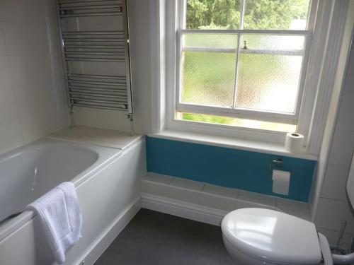 a bathroom with a tub and a toilet and a window at The Tally Ho in Hungerford