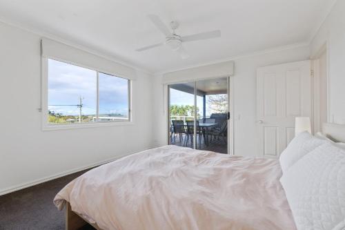 a white bedroom with a bed and a window at Sunrise at Smiths Beach in Smiths Beach