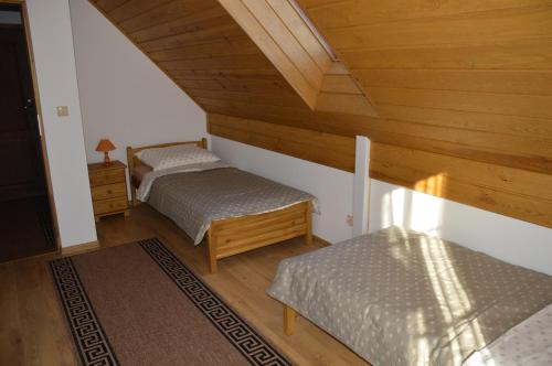 two twin beds in a room with wooden ceilings at Dom na Mazurach in Rydzewo