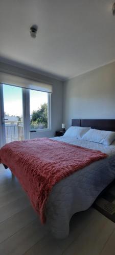 une chambre avec un grand lit recouvert d'une couverture rouge dans l'établissement Pucón Soñado Te Espera, à Pucón