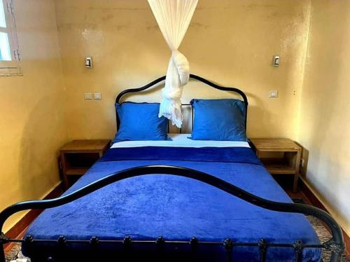 a bedroom with a blue bed with blue sheets and blue pillows at Petit Studio - île de Gorée in Gorée