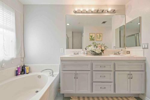 un bagno bianco con vasca e grande specchio di Beautiful 3B2B home with piano in Pasadena Oldtown a Pasadena