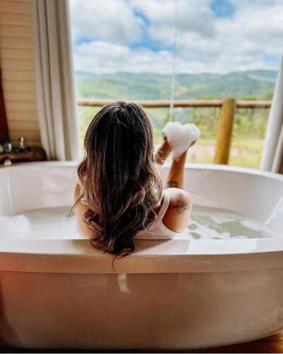a woman sitting in a bath tub with her hair at Chalés Altos da Serra - Chalé Pinhão em Urubici SC in Urubici