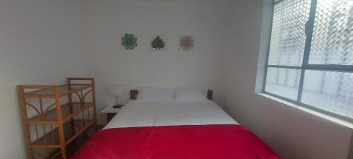 a small bedroom with a bed with a red blanket at Chasqui Jr. in Hacienda San Luis