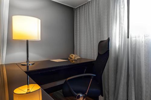 een kamer met een bureau met een stoel en een lamp bij ELEGANCE SUÍTES BERRINI in Sao Paulo