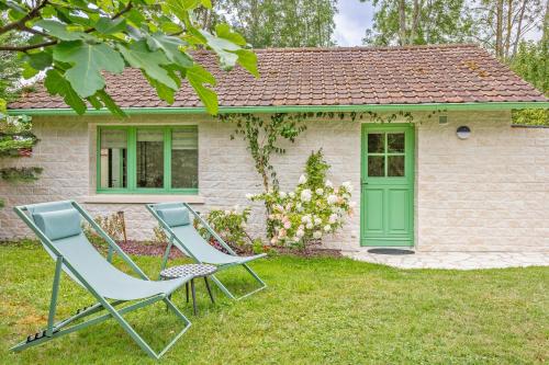 two chairs and a house with a green door at L'Orée de Giverny in Limetz