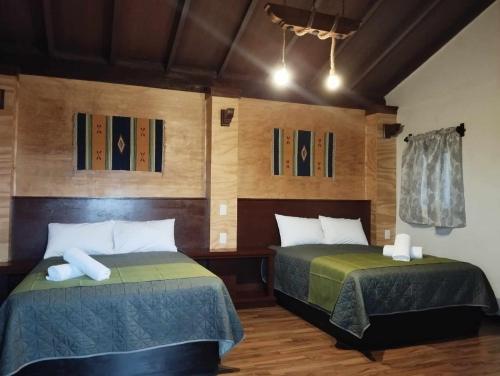 two beds in a room with wooden walls at Hotel & Cabañas Malinche in Huamantla