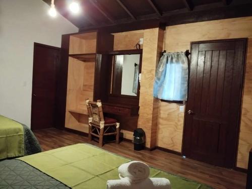 a bedroom with a bed and a door and a chair at Hotel & Cabañas Malinche in Huamantla