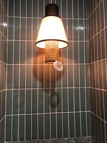 a light in a bathroom with a tiled wall at Comfy Room With Single Sized Bed, Study Space, Closet, and WiFi in Manila