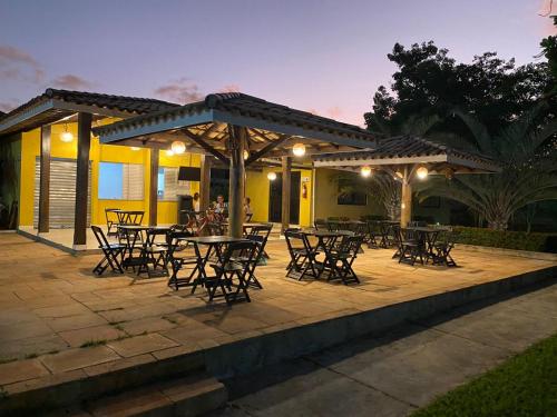 a patio with tables and chairs under a pergola at Casa amarela in Campos