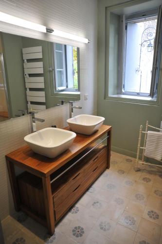 deux lavabos sur un comptoir en bois dans une salle de bain dans l'établissement Domaine de Ceyrac, à Conqueyrac