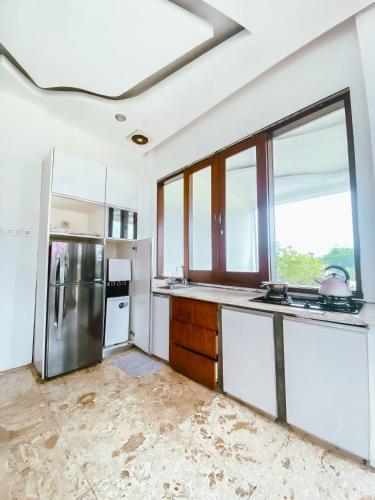 a kitchen with white cabinets and a large window at De Summit Villa & View in Puncak