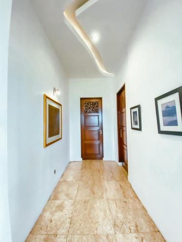 a hallway with white walls and a wooden door at De Summit Villa & View in Puncak