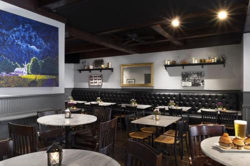 une salle à manger avec des tables et des chaises ainsi qu'une grande peinture murale. dans l'établissement Seven Gables Inn, St Louis West, a Tribute Portfolio Hotel, à Saint-Louis