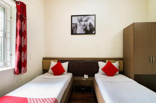 2 bedden in een kamer met rode en witte kussens bij OYO Flagship 1805 Hotel Star Delight in Pānchuria