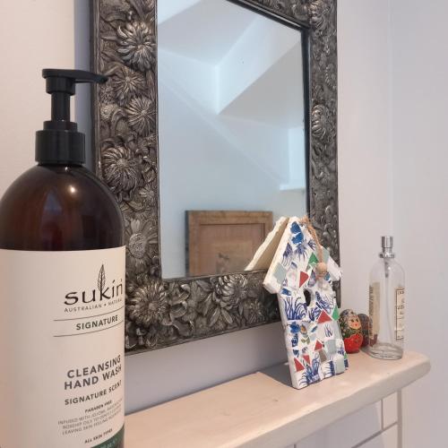 a bottle of wine sitting on a shelf next to a mirror at Hideaway Cottage - Private ensuite room - 4 minutes to the sea! in Sandgate