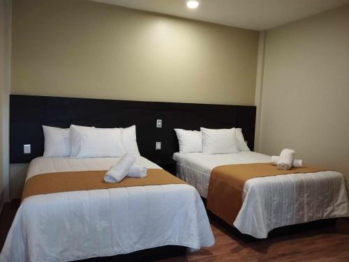 two beds in a hotel room with towels on them at Hotel & Cabañas Malinche in Huamantla