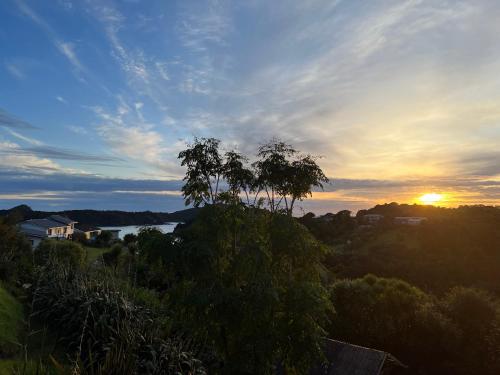 a sunset over a river with a tree in the foreground at Tutukaka Sunrise in Tutukaka