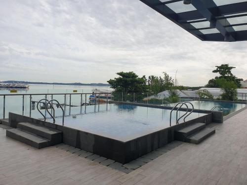 a large swimming pool next to a body of water at CozyHomes at One Residence Batam in Batam Center