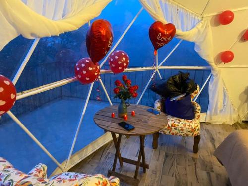a woman sitting at a table in a room with balloons at Luz de Luna Glamping in Pueblo Nuevo
