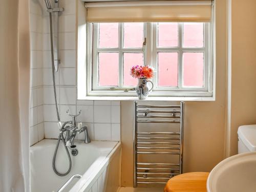 a bathroom with a tub and a window and a sink at Little House On The Common in Wortham