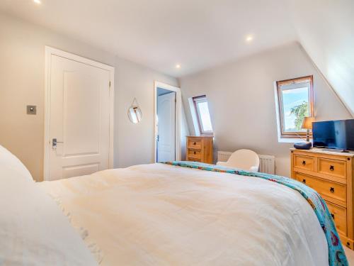 1 dormitorio con 1 cama blanca grande y TV en The Oast House, en Saffron Walden