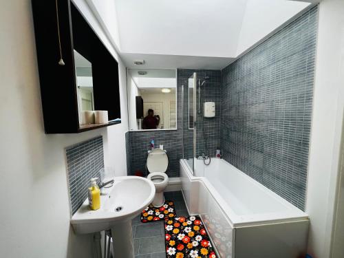 a bathroom with a sink and a toilet and a tub at Liberty Inn Room with sharing toilet and kitchen in Liverpool