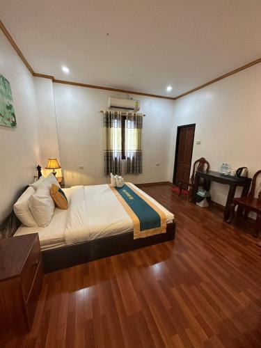 a large bed in a room with a wooden floor at Villa Mahasok hotel in Luang Prabang