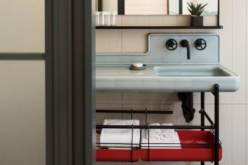 a bathroom with a sink and towels on a rack at Moxy NYC Chelsea in New York