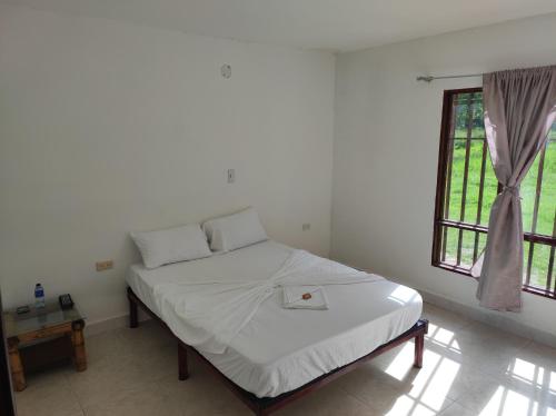 a bedroom with a bed with white sheets and a window at Hospedaje villa luz in Pitalito