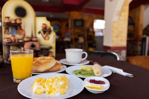 a table with plates of breakfast food and a cup of orange juice at Hostal Sonia in Copacabana