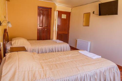 a hotel room with two beds and a flat screen tv at Hostal Sonia in Copacabana