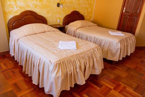 two beds with white sheets in a room with wood floors at Hostal Sonia in Copacabana
