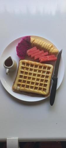 a plate with waffles and a knife on a table at Reureuh Cabin in Batukaras