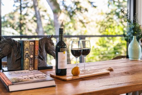 a bottle of wine and two glasses on a wooden table at Fig Tree Nest in Montville