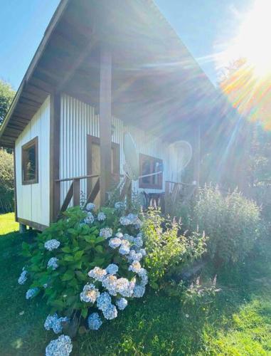 a small house with flowers in front of it at Tierra Azul ....Aires de cordillera. in Arrayán