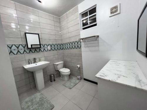 uma casa de banho branca com um lavatório e um WC em Chalet Belizomi Tropical Villas Studio Villa #3 em Gros Islet