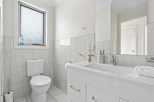 uma casa de banho branca com um WC e um lavatório em Stylish and Spacious Launceston Villa + Free Wifi em Launceston