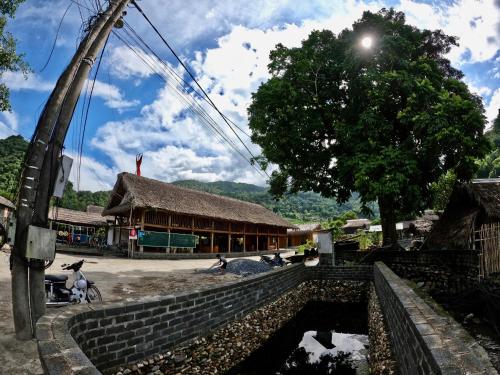 a village with a building in the background and a tree at Thavill Retreat HaGiang in Ha Giang