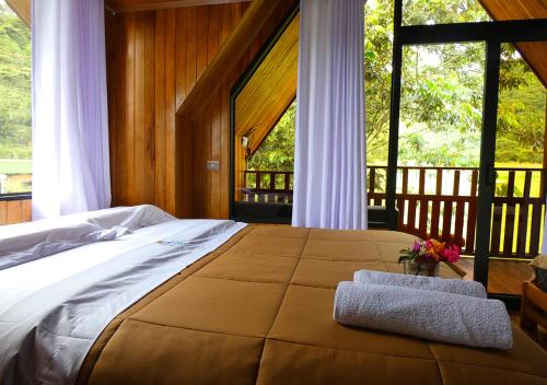 een slaapkamer met een groot bed en een groot raam bij Kusi Lodge in Oxapampa