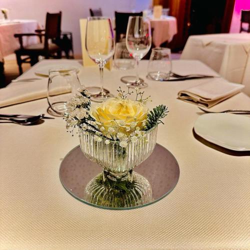 a table with a glass vase with flowers on it at Hôtellerie Du Bas-Bréau in Barbizon