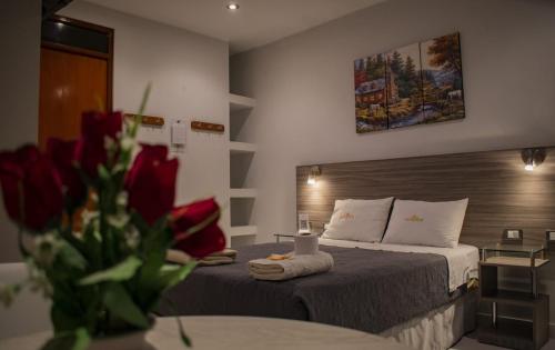 a hotel room with two beds and a table with red roses at Millennium Hotel in San Vicente de Cañete