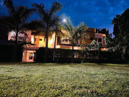 a building with palm trees in front of a yard at The HeartWood Farms Inn in Rāmnagar