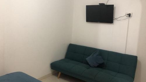 um sofá verde num quarto com uma televisão em Guacamayas em Santa Marta
