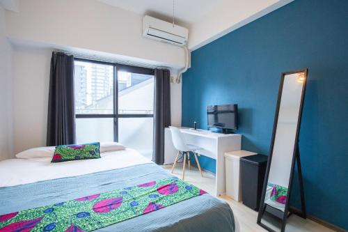 ein Schlafzimmer mit einem Bett, einem Schreibtisch und einem Spiegel in der Unterkunft Escort Haruyoshi in Fukuoka
