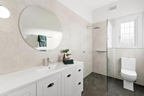 Baño blanco con lavabo y espejo en NEWLY RENOVATED LARGE 3.5 BDRM HOUSE! BEST OF MELB en Melbourne