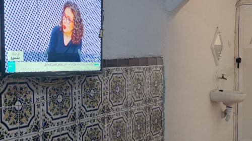 uma televisão numa parede numa casa de banho com um lavatório em casa de SMR em Chefchaouen