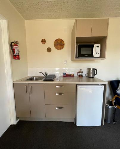 a small kitchen with a sink and a refrigerator at Colonial Motel in Twizel
