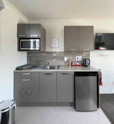 a kitchen with a sink and a microwave at Colonial Motel in Twizel