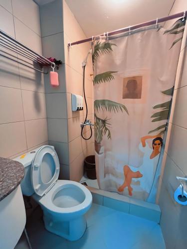 a bathroom with a toilet and a shower curtain at Albergo Condotel - AB Enterprise in Baguio